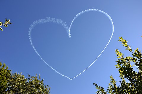 Flygplansrök som formar ett hjärta på himlen.