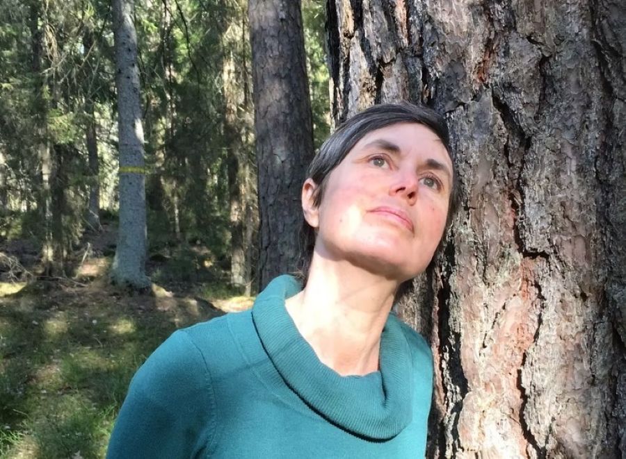 En kvinna står lutad mot ett träd.