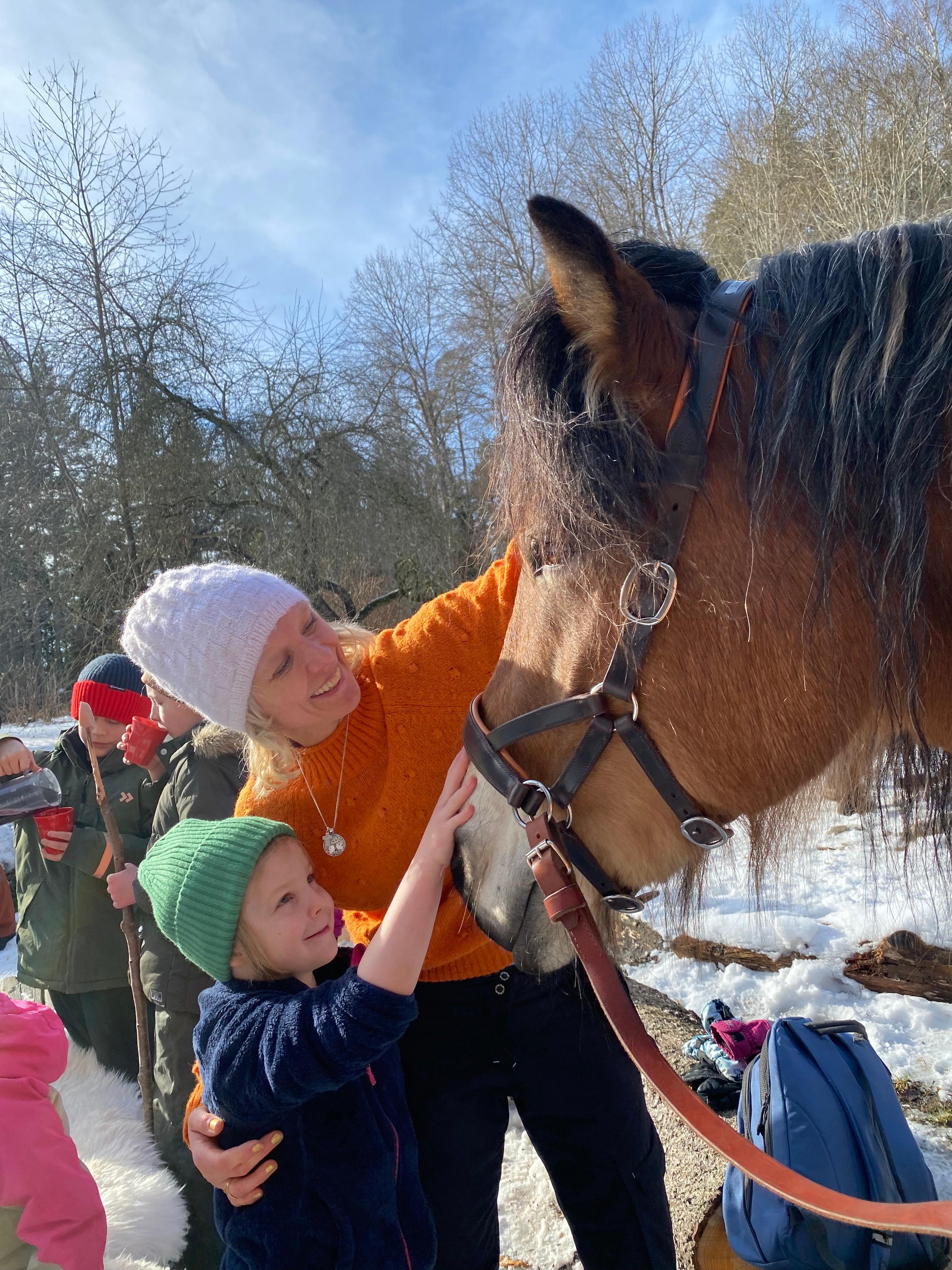 Ett barn och en vuxen klappar en häst.
