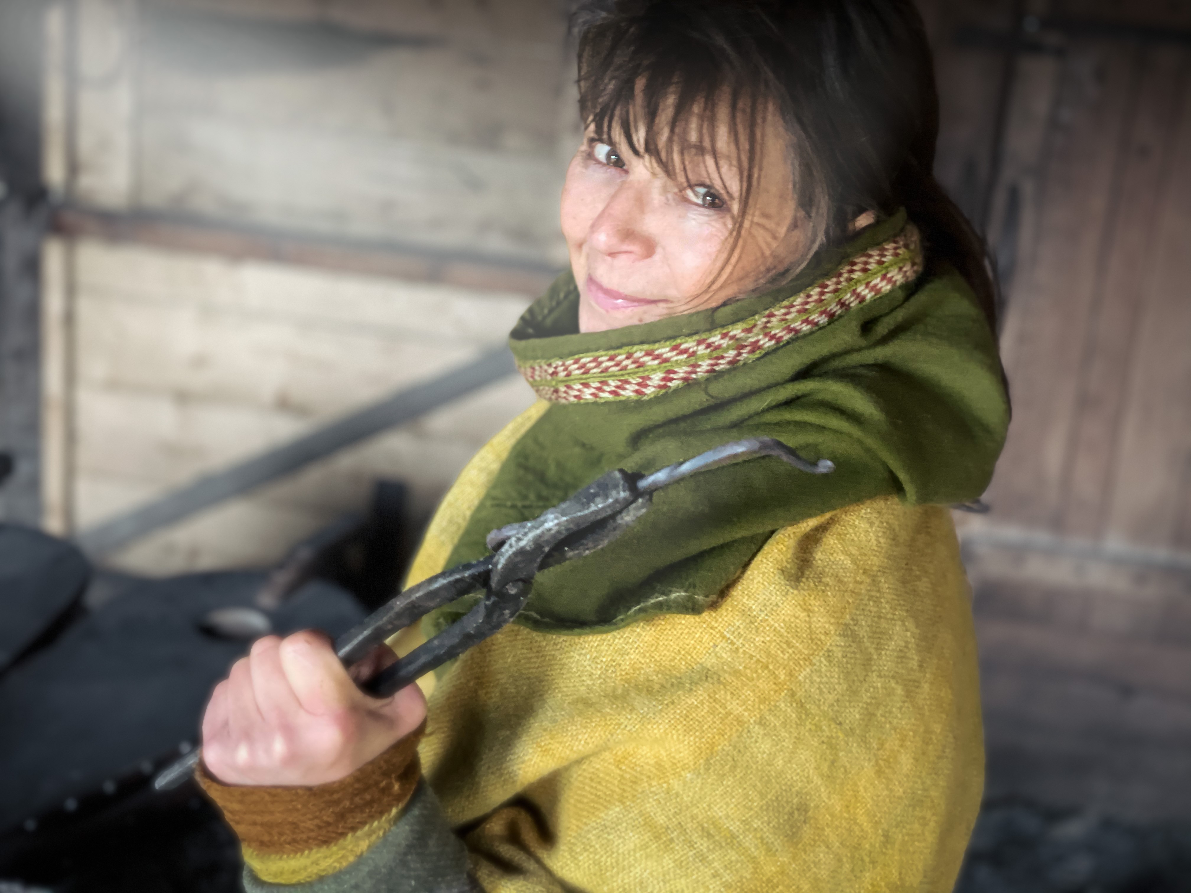 En kvinna håller i ett verktyg av järn och kollar mot kameran.