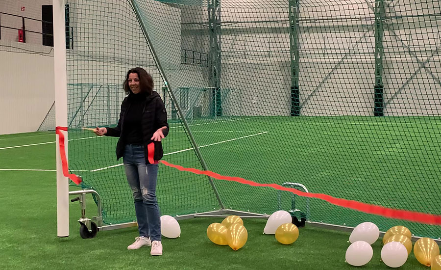 En person står i ett fotbollsmål med en sax i handen och ballonger i bakgrunden.
