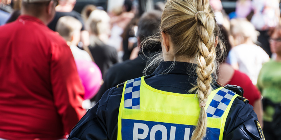 Poliskvinna i uniform och mindre grupp människor. 