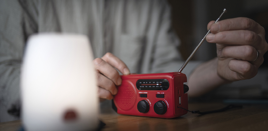 Person ställer in en röd vevradio.