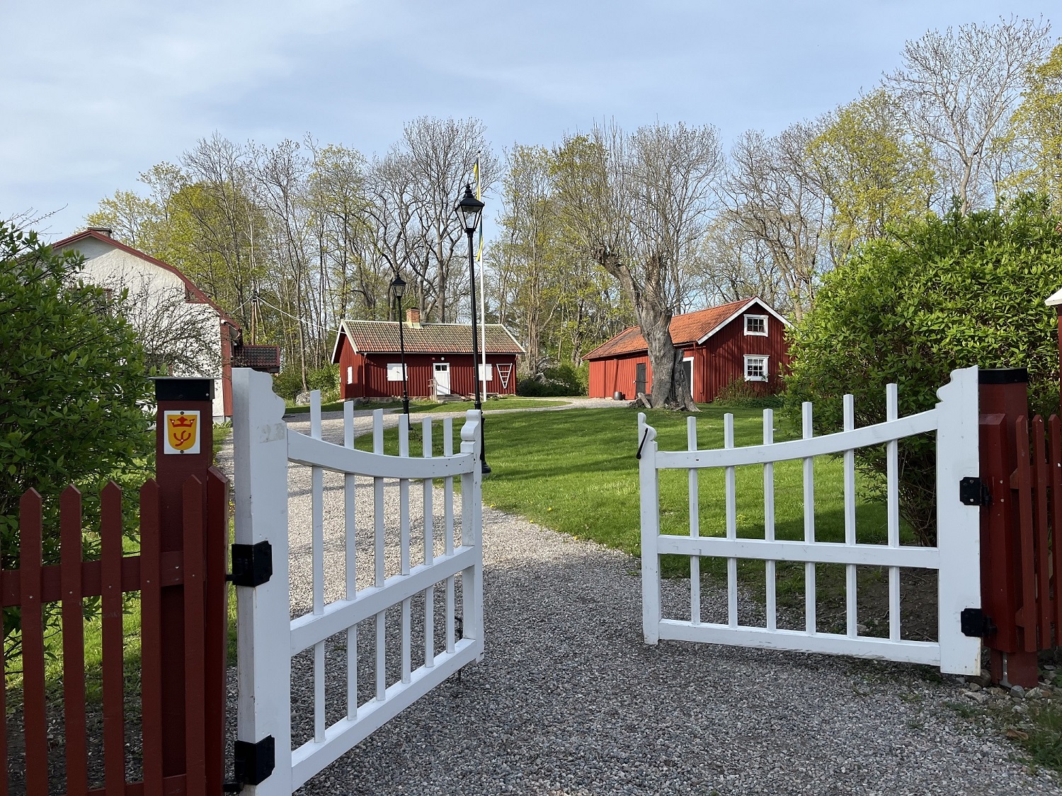Röda hus med vita detaljer. En grind och en grusgång.