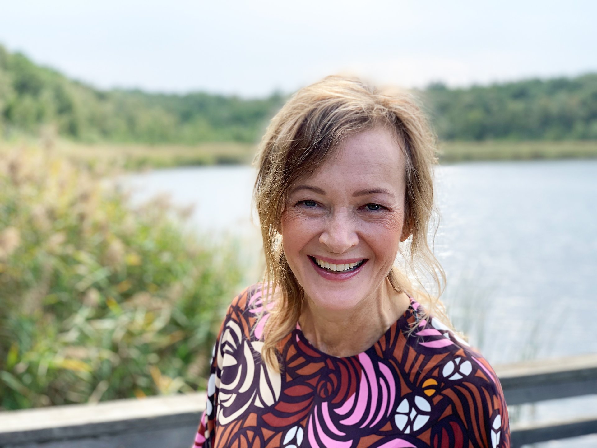 En kvinna ler stort och tittar in i kameran.