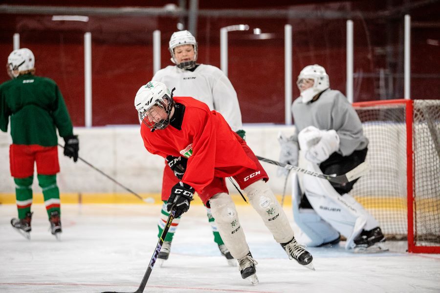 Två elever som spelar hockey. En tränare.