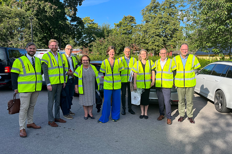 Bild tagen utomhus på landshövding, tjänstepersoner från Länsstyrelsen Stockholm och politiker och kommundirektörer från Upplands Väsby och Vallentuna kommun. I bakgrunden syns blå himmel och gröna träd.