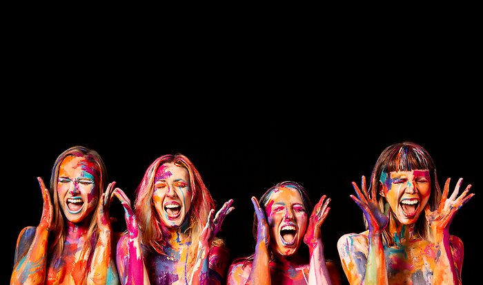 Fyra färgglatt målade kvinnor som skrattar