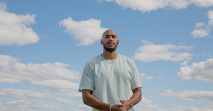 En man i T-shirt mot en blå himmel med vita moln