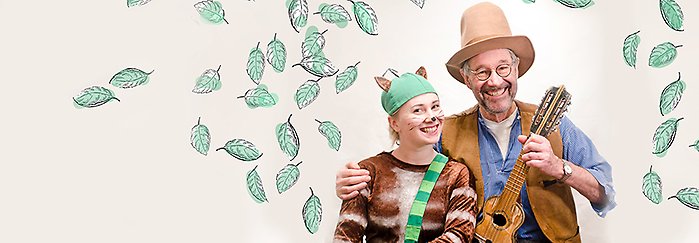 Två skådespelare utklädda till Pettson och katten Findus, mot ljus blommig bakgrund.
