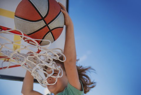 Ett barn träffar basketkorgen med sin basketboll.
