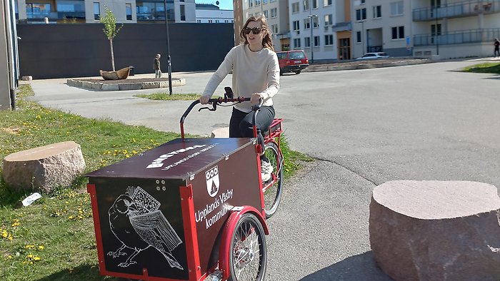 Kvinna på cykel med stor boklåda