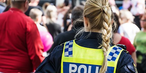 Poliskvinna i uniform och mindre grupp människor. 