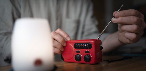 Person ställer in en röd vevradio.