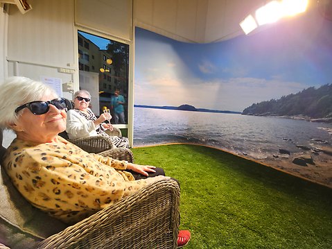 Två äldre damer sitter i ett rum som ger både ljus och värme.