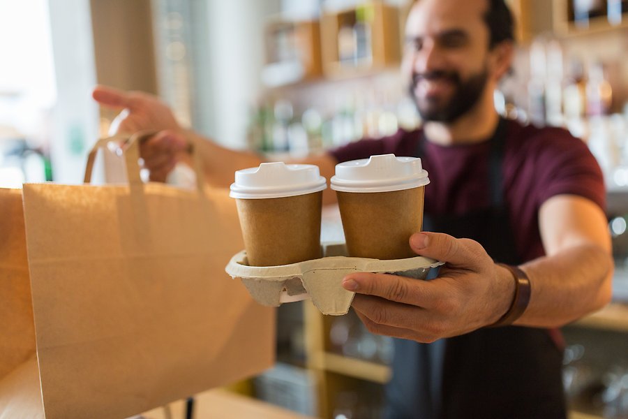 En caféanställd företagare serverar två muggar med kaffe till en kund