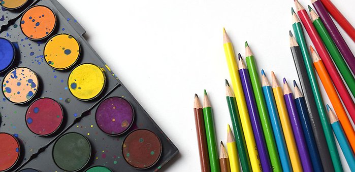 Färgglada pennor och vattenfärger på en vit yta